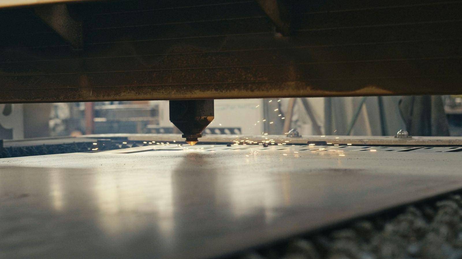 Representative photograph of a laser cutting head working a sheet metal plate